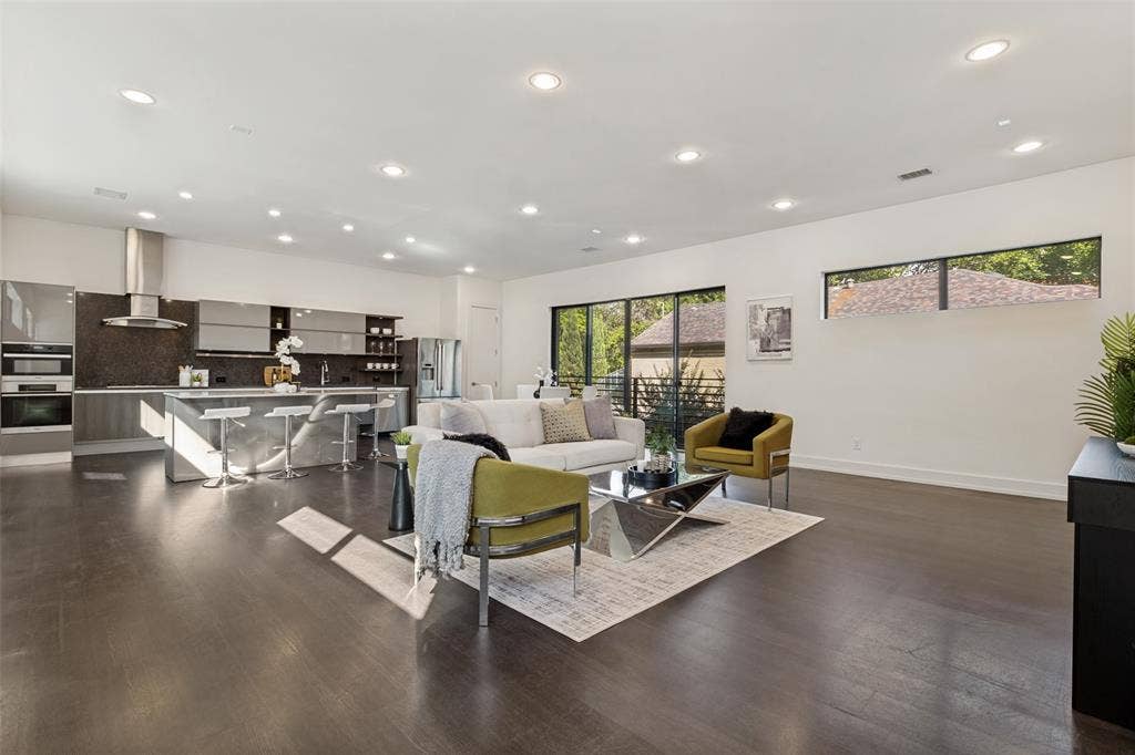 3336 Anchor Court, Dallas, TX 75219 Open-concept living space featuring wood-finish flooring, recessed lighting, expansive sliding glass doors, and a modern kitchen with a large island and stainless steel range hood