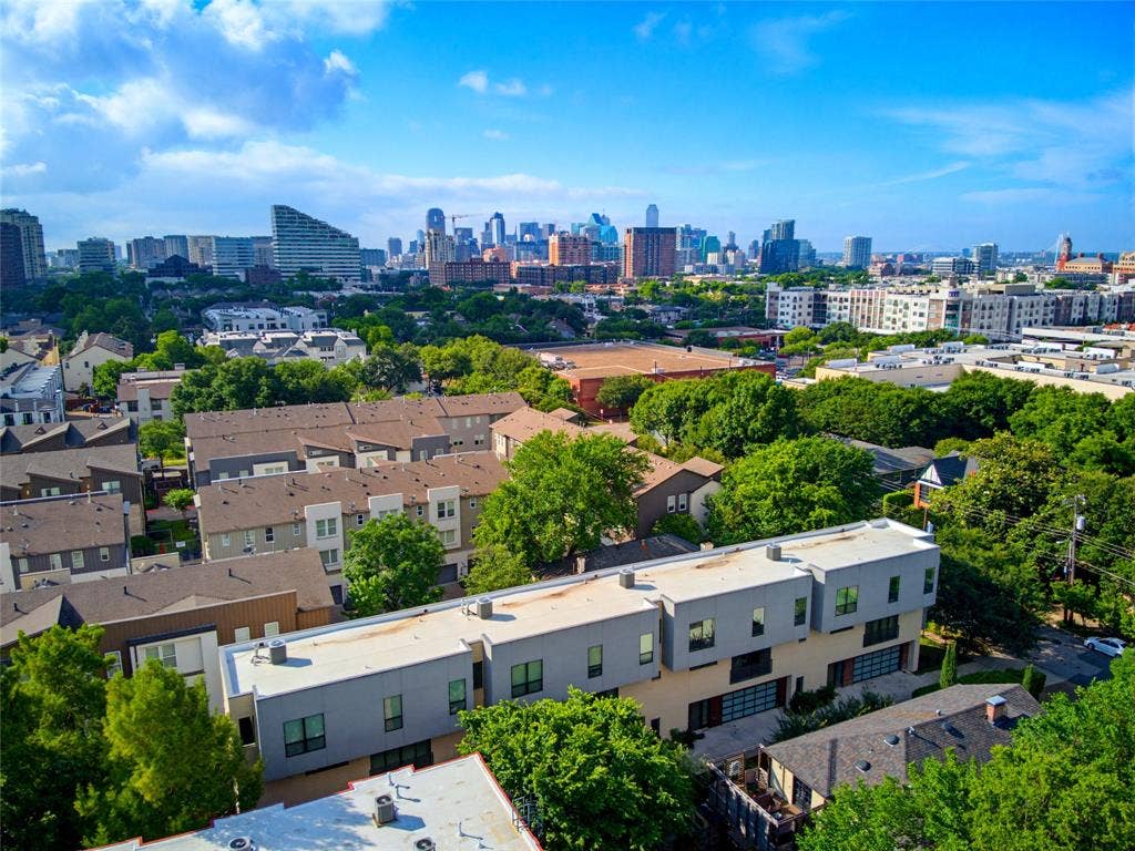 3336 Anchor Court, Dallas, TX 75219 Aerial perspective of a multi-level structure featuring a flat roofline, grey and cream exterior cladding, large glass panel garage doors, and a paved driveway