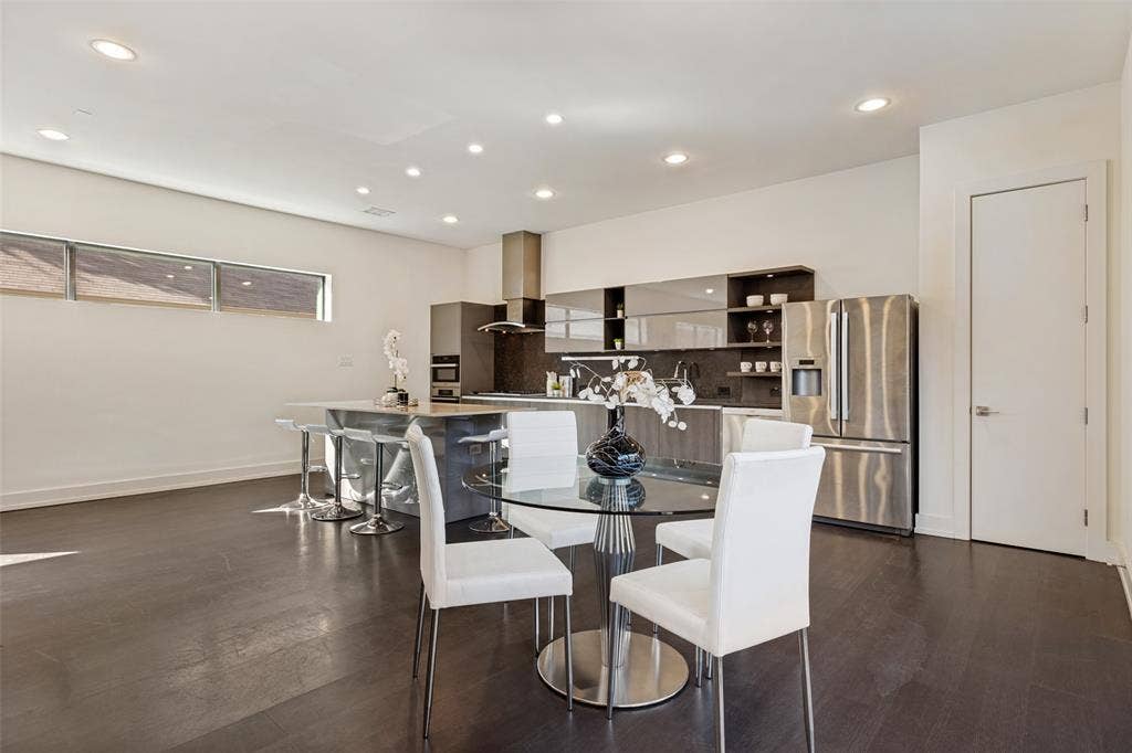 3336 Anchor Court, Dallas, TX 75219 Contemporary kitchen featuring dark wood-finish cabinetry, a waterfall-edge stone island, recessed ceiling lighting, horizontal clerestory windows, and stainless steel appliances