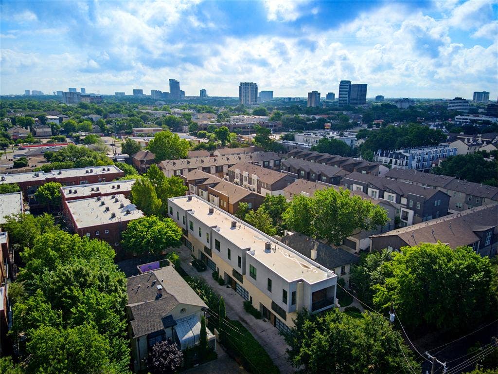 3336 Anchor Court, Dallas, TX 75219 Aerial perspective of a multi-level residential complex featuring a flat roofline, neutral exterior cladding, balcony, and urban skyline backdrop