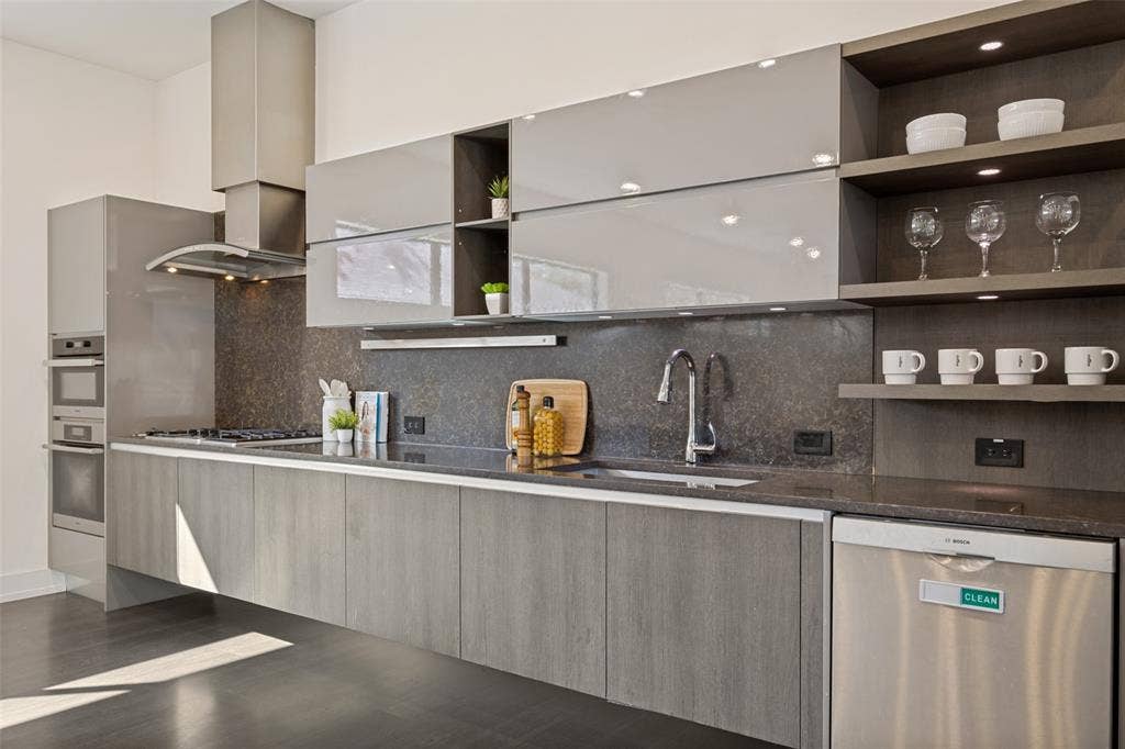 3336 Anchor Court, Dallas, TX 75219 Modern kitchen featuring high-gloss cabinetry, stone-finish countertops, floating base cabinets, a stainless steel range hood, and open display shelving with integrated lighting