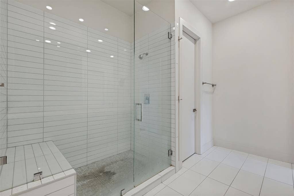 3336 Anchor Court, Dallas, TX 75219 Walk-in shower featuring a frameless glass enclosure, built-in tiled bench, horizontal wall tile, and recessed lighting