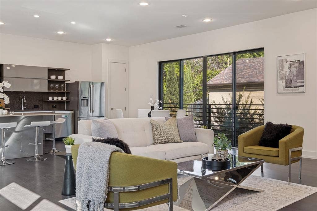 3336 Anchor Court, Dallas, TX 75219 Open-concept kitchen featuring metallic-finish cabinetry, stone-surface countertops, and recessed lighting, complemented by expansive glass sliding doors with black framing