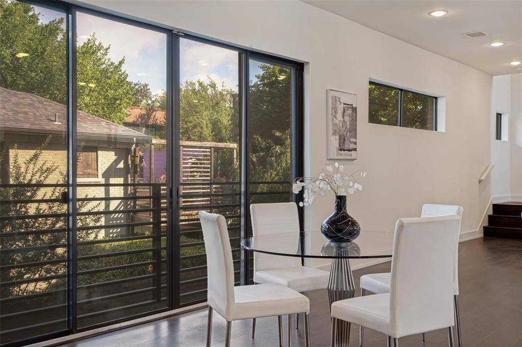 3336 Anchor Court, Dallas, TX 75219 Floor-to-ceiling multi-panel sliding glass doors with dark frames, recessed lighting, dark wood-finish flooring, and horizontal window placement