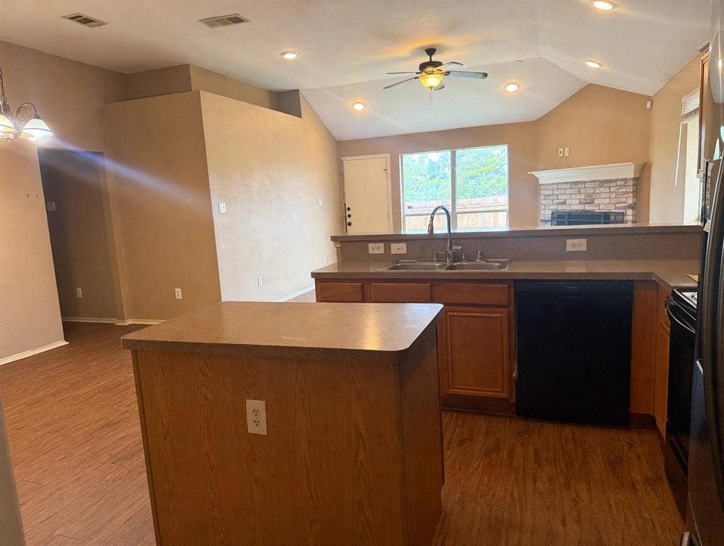 2053 Wild Creek Court, Dallas, TX 75253 Kitchen featuring a central island, wood-finish cabinetry, vaulted ceilings with recessed lighting, and a brick-surround fireplace