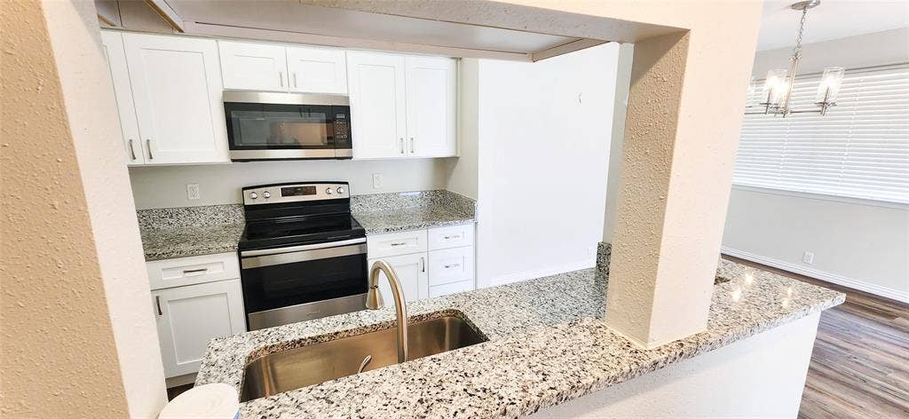 4402 Tophill Lane, Irving, TX 75038 Kitchen featuring white cabinetry, stone countertops, stainless steel appliances, a stainless steel undermount sink with a gooseneck faucet, and wood-finish flooring