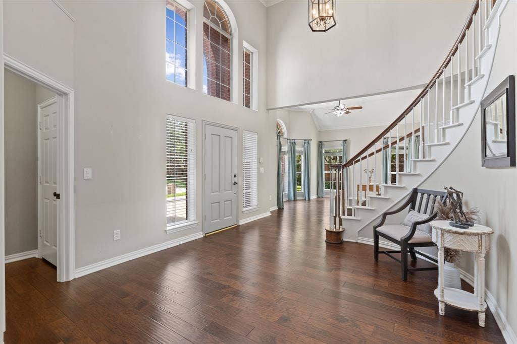 1110 Wedge Hill Road, McKinney, TX 75072 Foyer featuring vaulted ceilings, wood-finish flooring, a sweeping staircase with white balusters, multi-pane arched windows, and a suspended lantern-style fixture