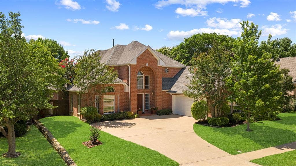 1110 Wedge Hill Road, McKinney, TX 75072 Brick exterior residence featuring an arched entryway, a steep-pitched roof, an attached two-car garage, and manicured landscaping with stone-retaining walls