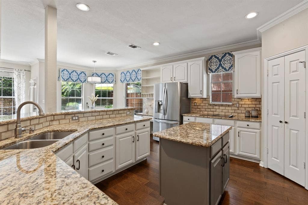 1110 Wedge Hill Road, McKinney, TX 75072 Kitchen featuring stone countertops, white cabinetry, a center island, brick-style tile backsplash, and wood-finish flooring