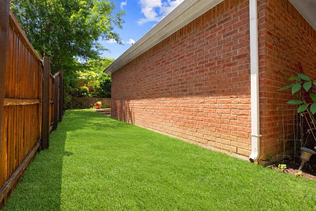 1110 Wedge Hill Road, McKinney, TX 75072 Exterior side yard featuring a brick facade, full-height privacy fencing, and a manicured lawn