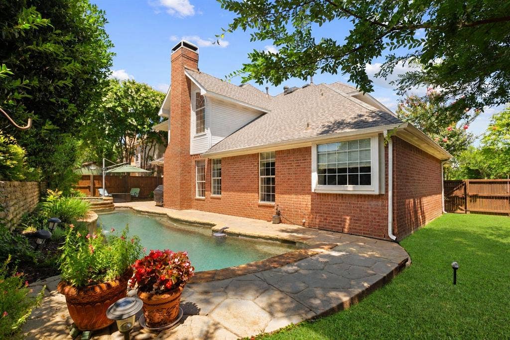 1110 Wedge Hill Road, McKinney, TX 75072 Brick exterior with an external chimney, flagstone patio, in-ground swimming pool, and landscaped yard enclosed by wood fencing