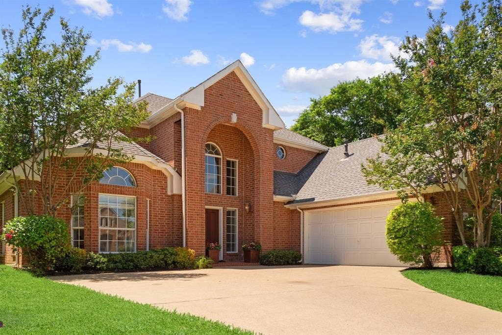 1110 Wedge Hill Road, McKinney, TX 75072 Traditional brick exterior featuring a prominent arched entryway, gabled roofline, multi-pane arched windows, and a multi-car garage