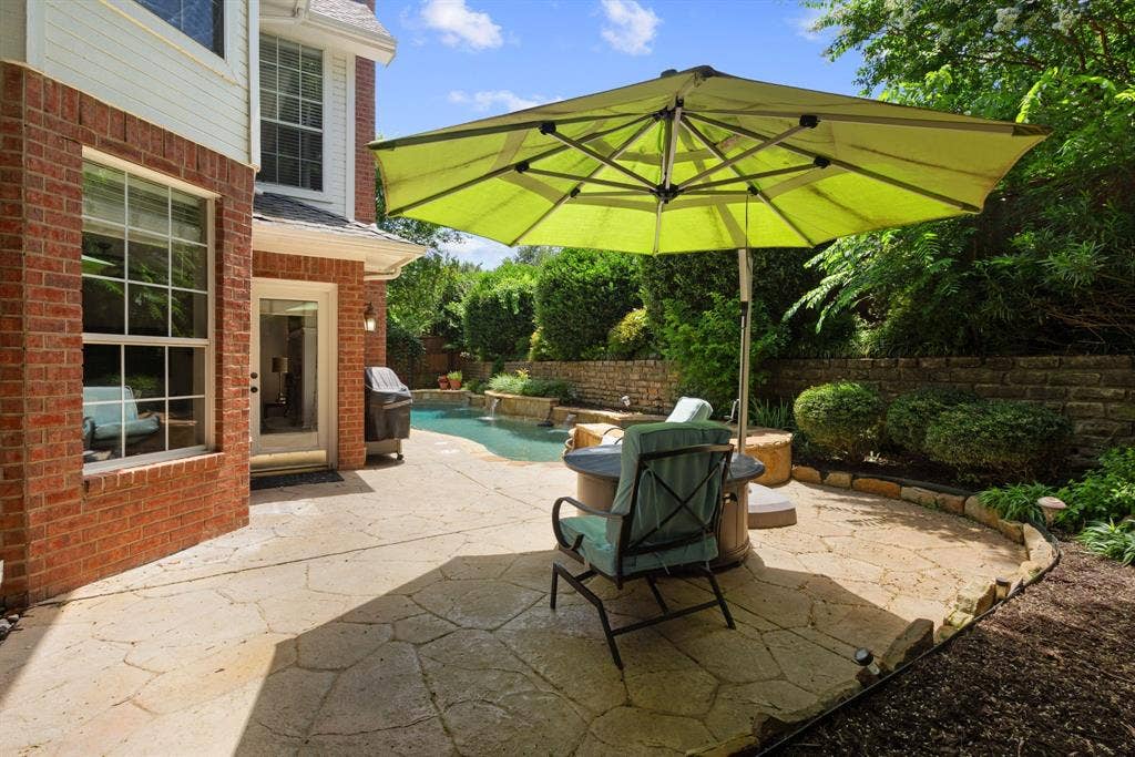 1110 Wedge Hill Road, McKinney, TX 75072 Flagstone patio featuring an in-ground pool, stacked stone retaining wall, and red brick exterior finish