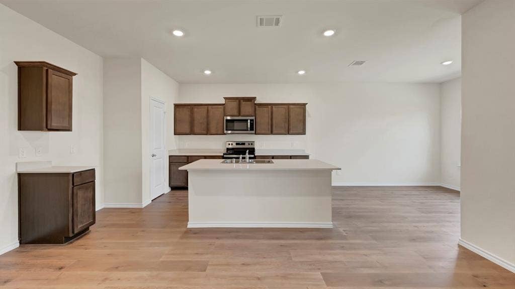 4033 Ripplewood Drive, Lindale, TX 75771 Expansive kitchen with an island, wood-finish flooring, recessed lighting, and dark wood cabinetry
