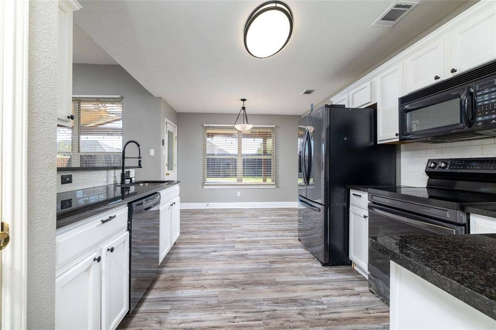 224 Cobblestone Circle, Red Oak, TX 75154 Kitchen featuring white cabinetry, dark stone countertops, wood-finish flooring, a matte black faucet, and built-in black appliances