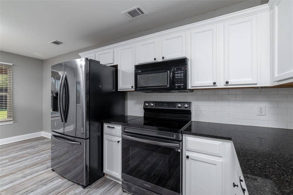 224 Cobblestone Circle, Red Oak, TX 75154 Kitchen featuring white shaker-style cabinetry, dark stone countertops, white subway tile backsplash, and stainless steel appliances