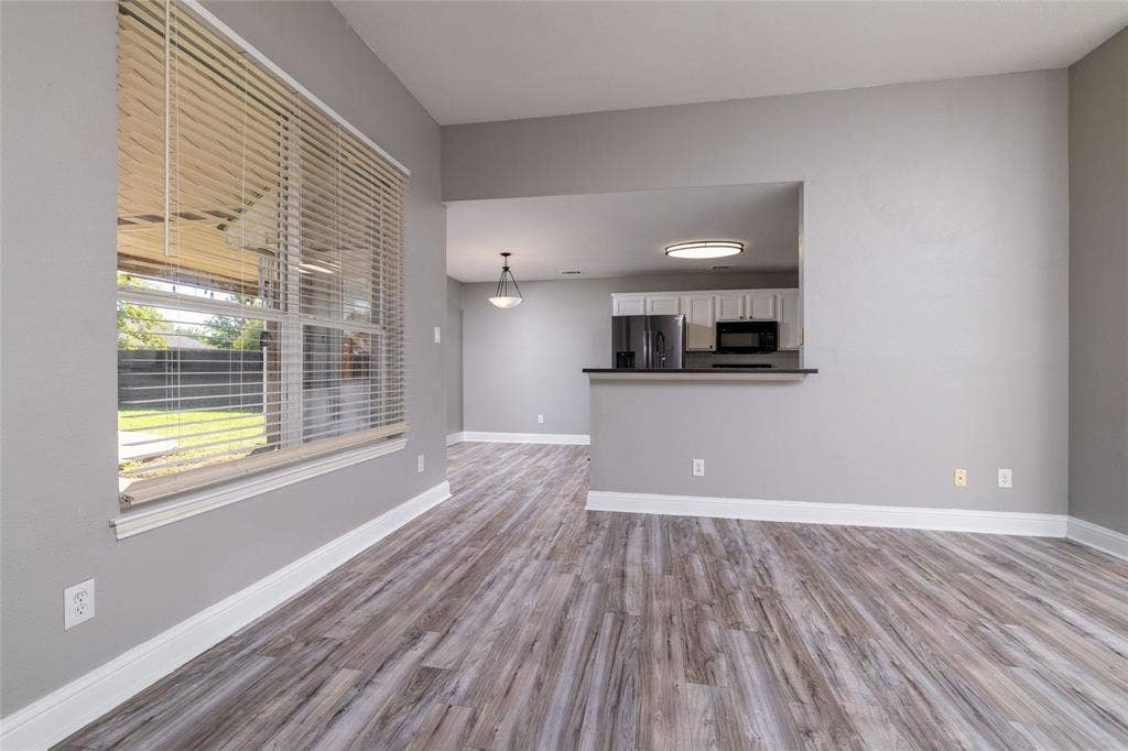 224 Cobblestone Circle, Red Oak, TX 75154 Wood-finish flooring, large window with horizontal blinds, pass-through opening to kitchen, and breakfast bar