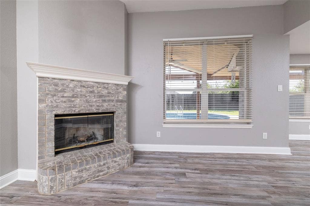 224 Cobblestone Circle, Red Oak, TX 75154 Fireplace with stone-finish masonry, elevated hearth, and white crown molding surround, paired with wood-finish flooring