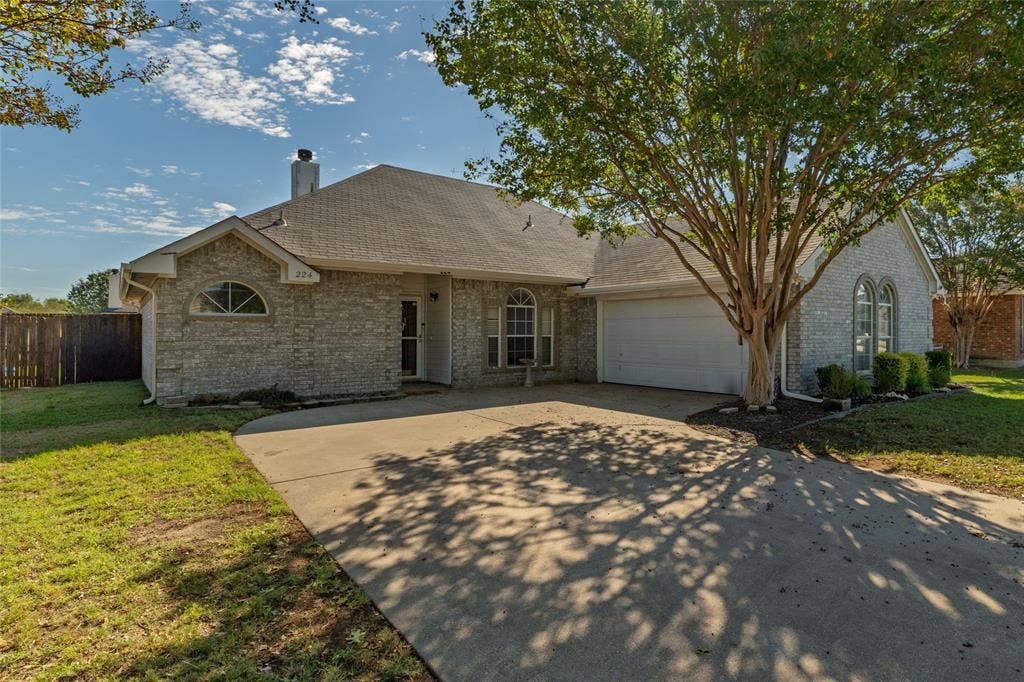 224 Cobblestone Circle, Red Oak, TX 75154 Single-story brick exterior featuring an arched window, attached two-car garage, concrete driveway, and mature landscaping