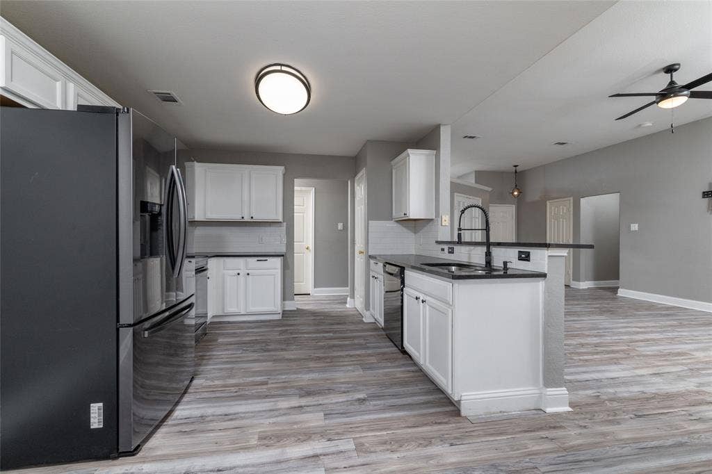 224 Cobblestone Circle, Red Oak, TX 75154 Kitchen featuring white cabinetry, dark countertops, wood-finish flooring, a matte black faucet, and stainless steel appliances