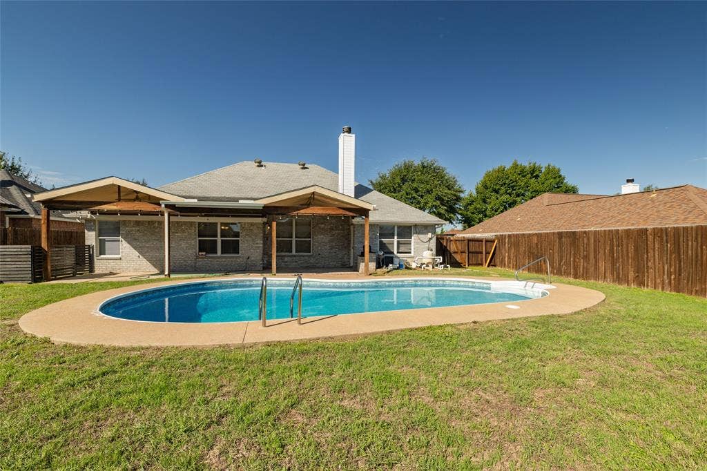 224 Cobblestone Circle, Red Oak, TX 75154 Backyard featuring an in-ground swimming pool, concrete pool deck, covered patio with wood supports, brick exterior, and wood privacy fencing