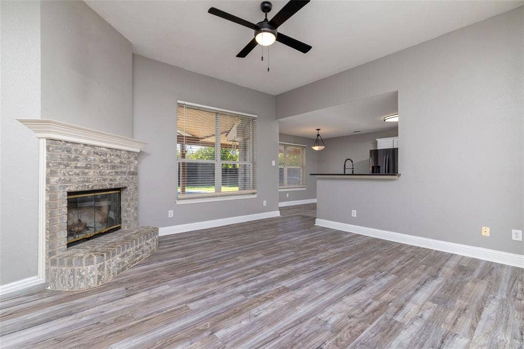 224 Cobblestone Circle, Red Oak, TX 75154 Living area featuring wood-finish flooring, a brick fireplace with a mantel, and a black ceiling fan