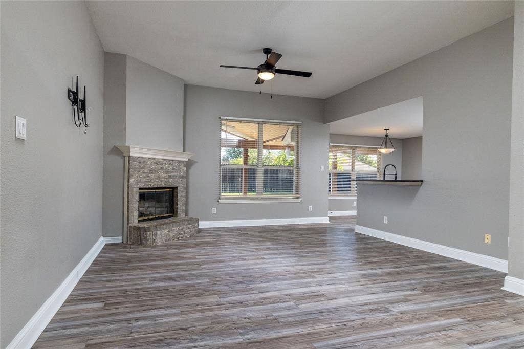 224 Cobblestone Circle, Red Oak, TX 75154 Living area featuring wood-finish flooring, stone-surround fireplace with mantel, ceiling fan, and bar-style pass-through