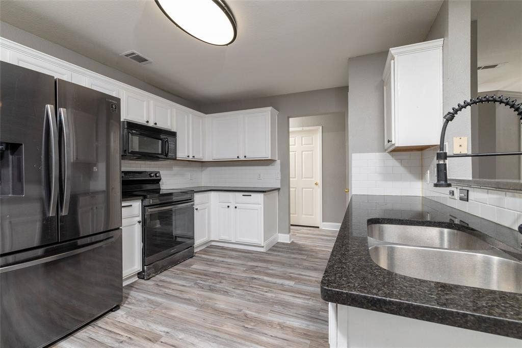 224 Cobblestone Circle, Red Oak, TX 75154 Kitchen featuring white shaker-style cabinetry, dark stone-finish countertops, subway tile backsplash, wood-finish flooring, and black appliances
