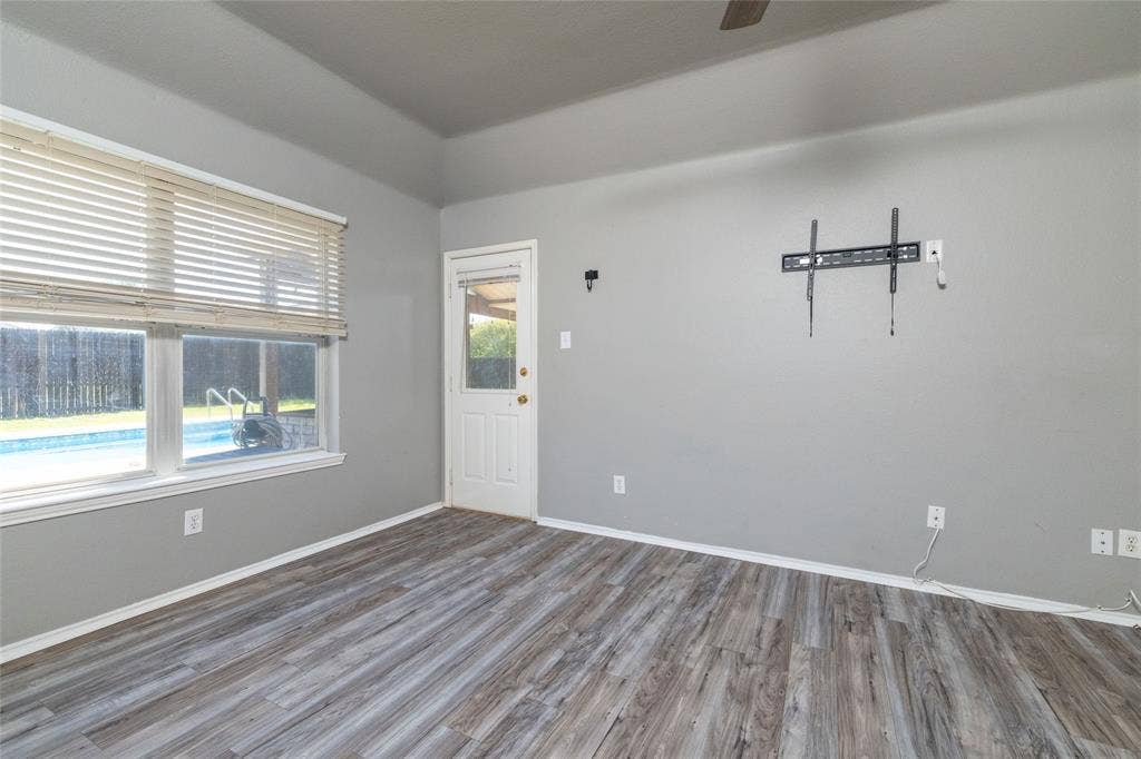 224 Cobblestone Circle, Red Oak, TX 75154 Interior space featuring wood-finish flooring, tray ceiling, large window with horizontal blinds, and exterior door with a glass insert