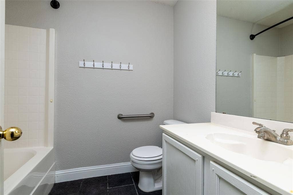 224 Cobblestone Circle, Red Oak, TX 75154 Full-width vanity featuring an integrated sink, polished metal faucet, white cabinetry, and a large wall-mounted mirror, paired with a shower-tub combination featuring tiled surround and a metal grab bar
