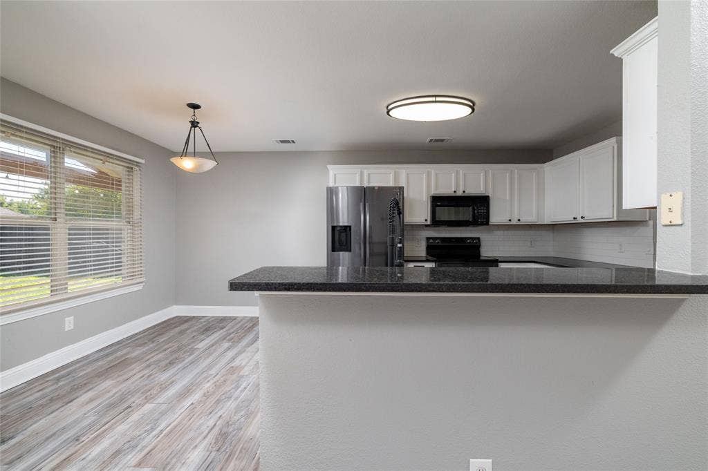 224 Cobblestone Circle, Red Oak, TX 75154 Kitchen featuring white cabinetry, dark stone-style countertops, stainless steel refrigerator, built-in microwave, and wood-finish flooring