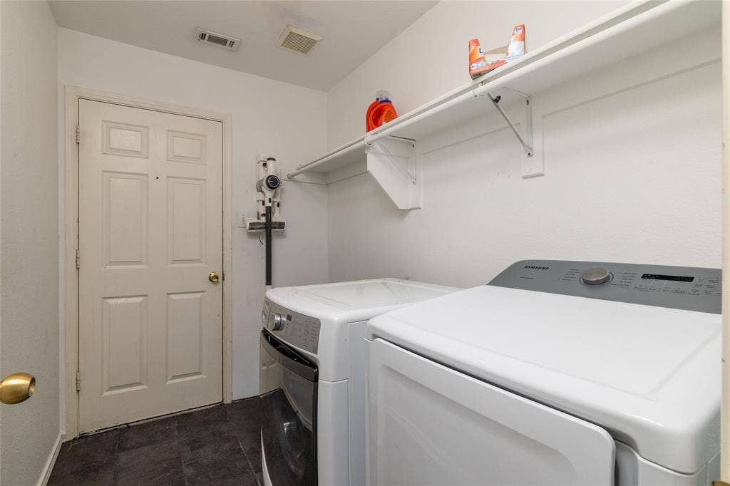 224 Cobblestone Circle, Red Oak, TX 75154 Laundry area featuring dark tile flooring, a six-panel door, and integrated wall-mounted shelving
