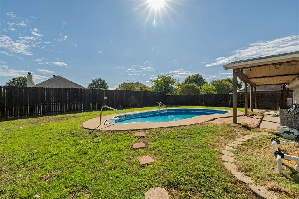 224 Cobblestone Circle, Red Oak, TX 75154 Private backyard featuring an in-ground swimming pool, concrete decking, covered patio, and wood privacy fencing