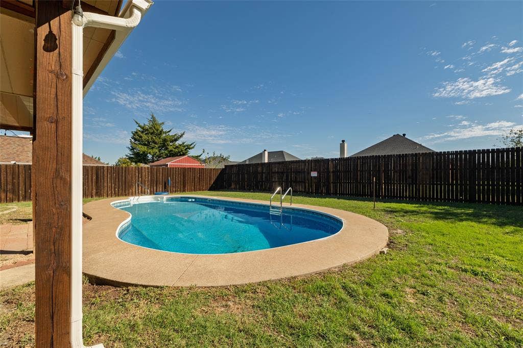 224 Cobblestone Circle, Red Oak, TX 75154 In-ground kidney-shaped swimming pool with a concrete surround, enclosed by a full-perimeter wood privacy fence and featuring a grassy lawn