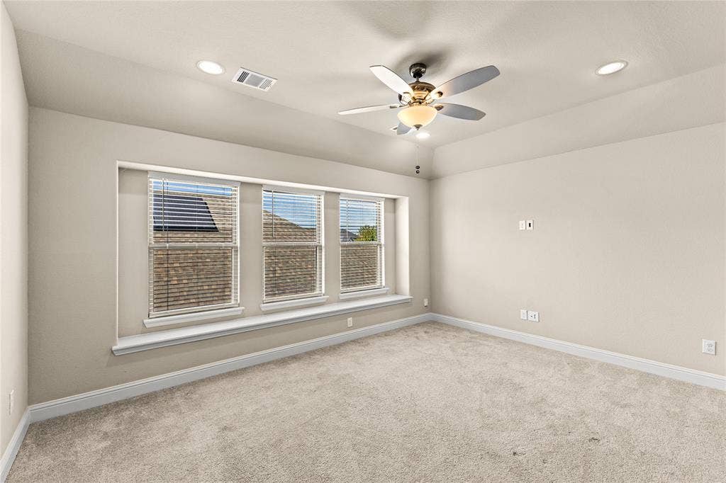 408 Abbott Lane, Waxahachie, TX 75165 Tray ceiling with a central multi-blade ceiling fan, recessed lighting, and a triple-window configuration featuring a built-in window seat