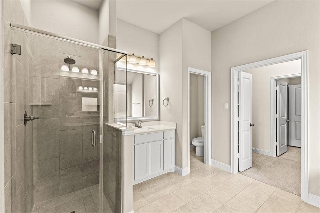 408 Abbott Lane, Waxahachie, TX 75165 Walk-in shower with stone-tile surround, vanity with cabinetry and integrated countertop, framed vanity mirror, and tile flooring