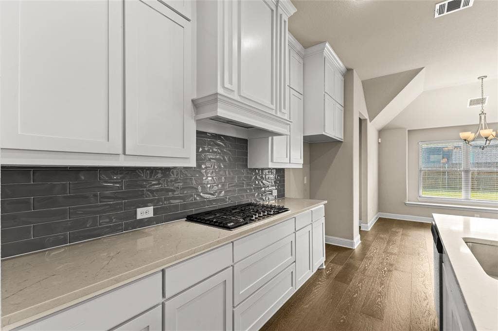 408 Abbott Lane, Waxahachie, TX 75165 Kitchen featuring white shaker-style cabinetry, quartz countertops, a charcoal-toned subway tile backsplash, gas cooktop, and wood-finish flooring