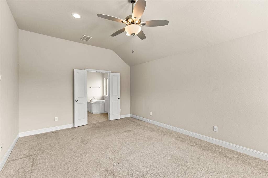408 Abbott Lane, Waxahachie, TX 75165 Vaulted ceiling featuring a central multi-blade ceiling fan with integrated light fixture, neutral wall finishes, and double doors opening to a space with tile flooring and a soaking tub