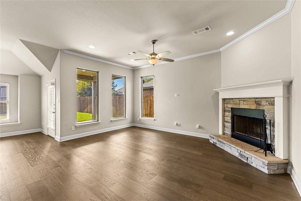 408 Abbott Lane, Waxahachie, TX 75165 Living area featuring wood-finish flooring, a stone-surround fireplace with a white mantel, neutral wall color, recessed lighting, and a ceiling fan