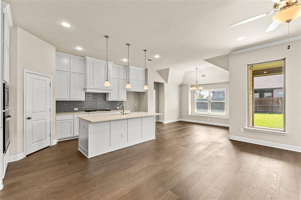 408 Abbott Lane, Waxahachie, TX 75165 Kitchen featuring white cabinetry, center island with stone-finish countertop, dark subway tile backsplash, recessed lighting, and wood-finish flooring