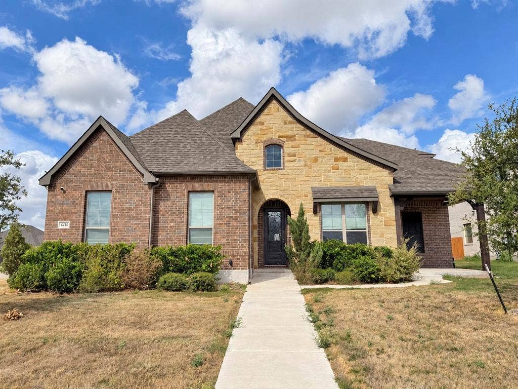 6414 Waggoner Court, Temple, TX 76502 Mixed-masonry exterior featuring brick and natural stone veneer, multi-gabled roofline, and arched entryway with a decorative glass-panel front door