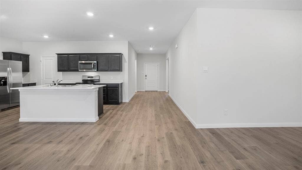 320 Ridan Drive, Waxahachie, TX 75165 Open-concept living area featuring wood-finish flooring, recessed lighting, and a white kitchen island