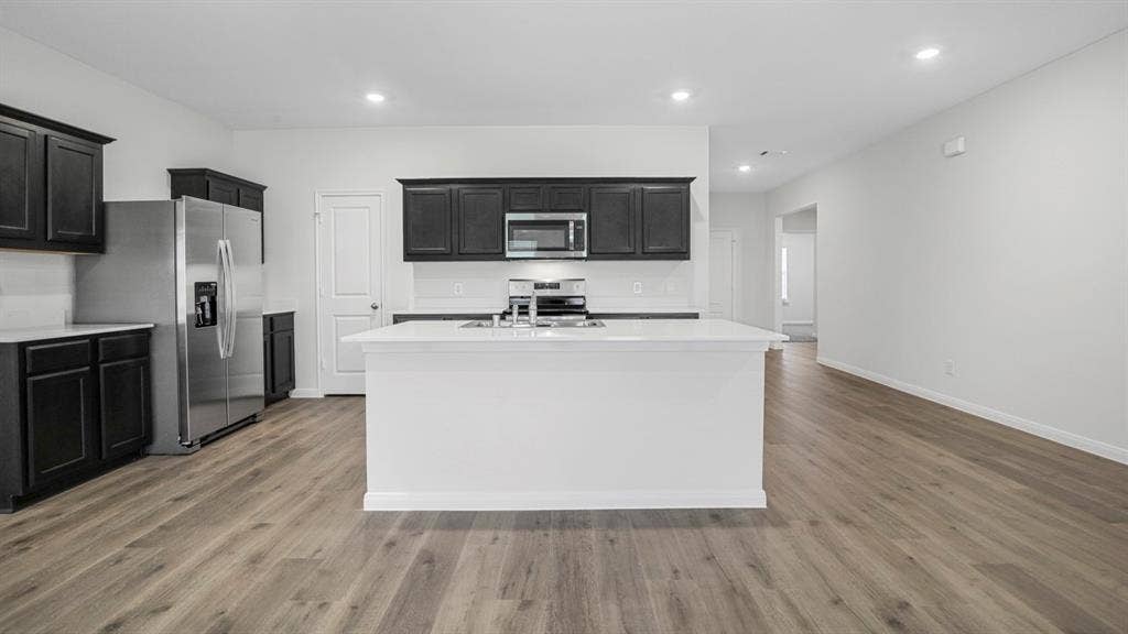 320 Ridan Drive, Waxahachie, TX 75165 Open-concept kitchen featuring dark wood cabinetry, white countertops, stainless steel appliances, and wood-finish flooring