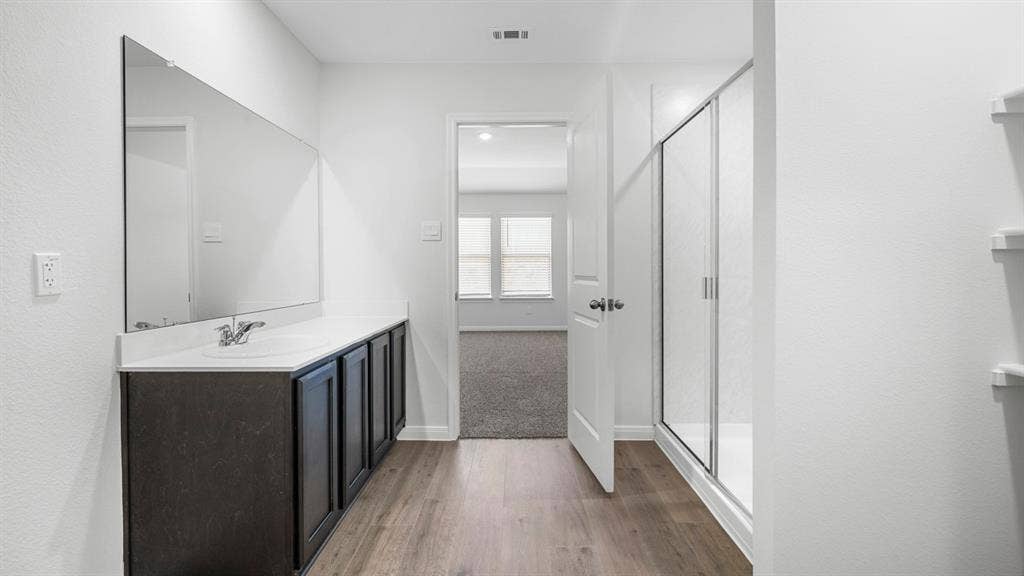 320 Ridan Drive, Waxahachie, TX 75165 Contemporary bathroom featuring wood-finish flooring and a vanity with a white countertop and dark cabinetry