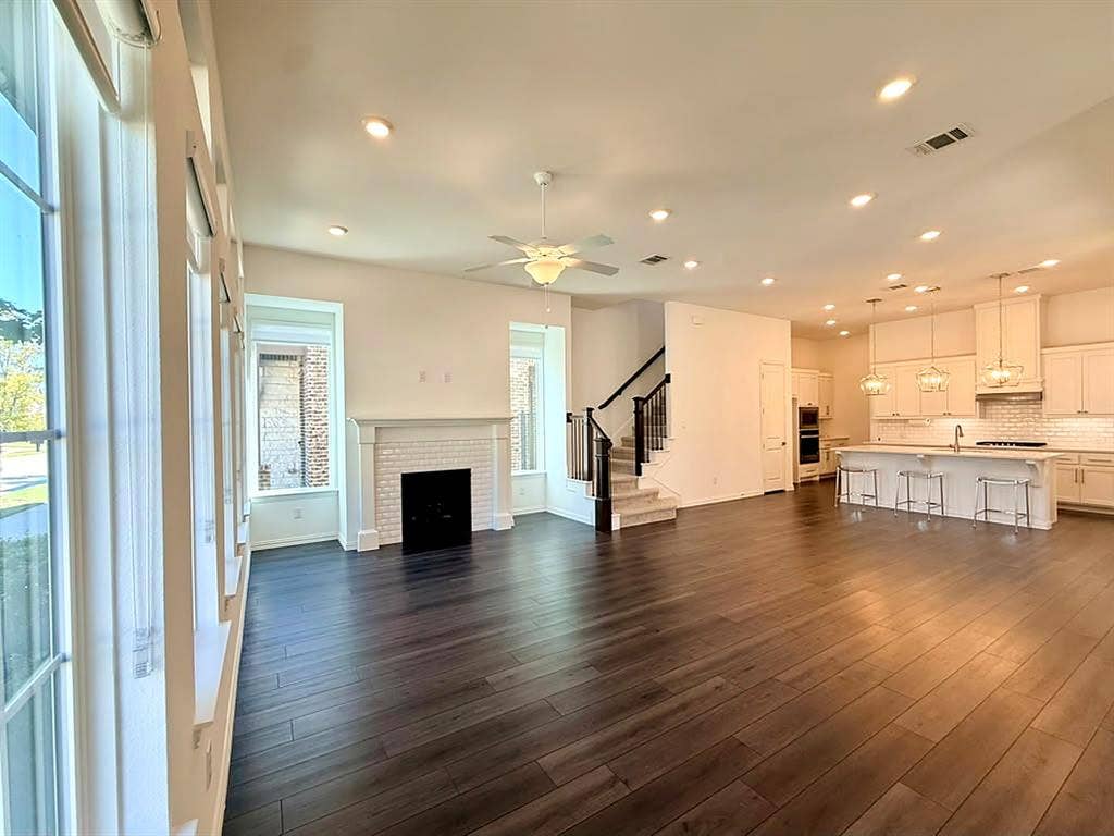8705 Bethpage Drive, McKinney, TX 75070 Open-concept floor plan, high ceilings, large windows, dark grand flooring, and a fireplace.