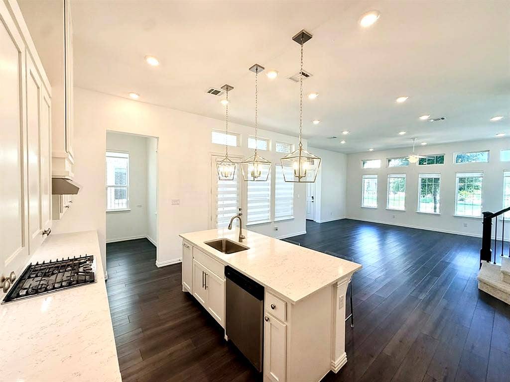 8705 Bethpage Drive, McKinney, TX 75070 White cabinetry, large center island, quartz-look countertops, gas cooktop, stainless steel appliances, and pendant lighting.