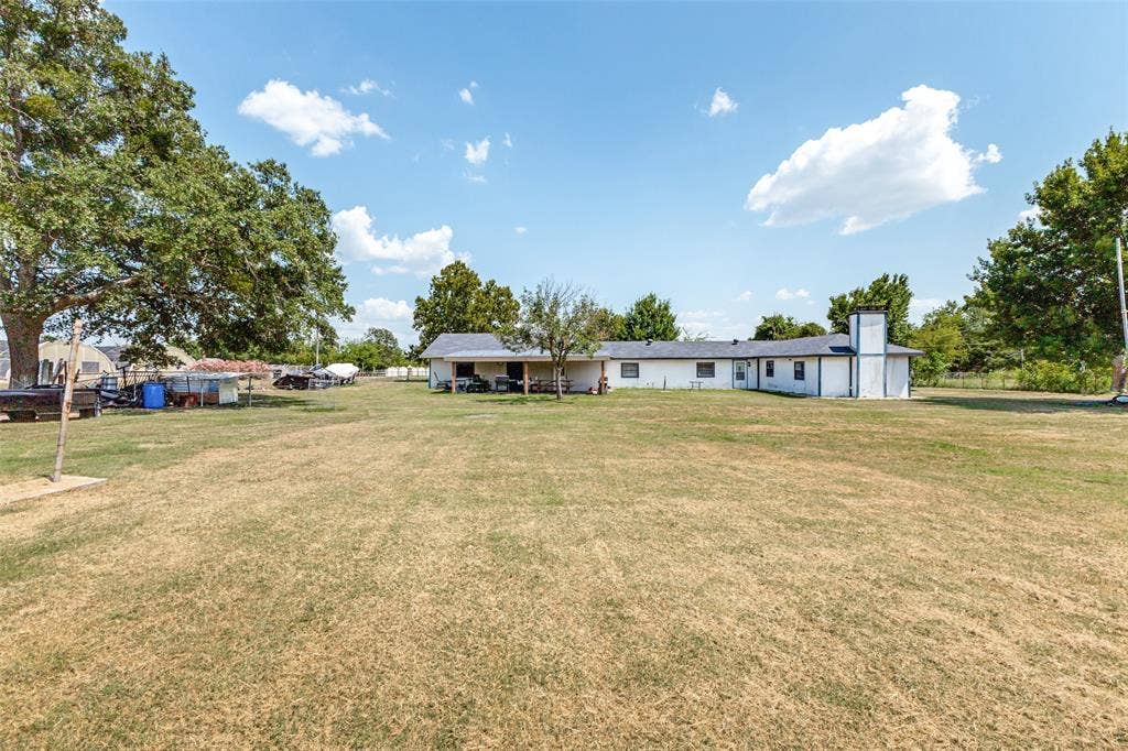 7400 County Road 131A, Terrell, TX 75161 Expansive grounds featuring mature shade trees, a covered patio, and a masonry chimney