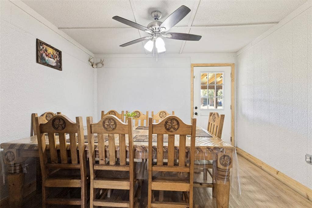 7400 County Road 131A, Terrell, TX 75161 Neutral-toned walls paired with wood-finish flooring, central ceiling fan with integrated lighting, and an exterior door with a window insert