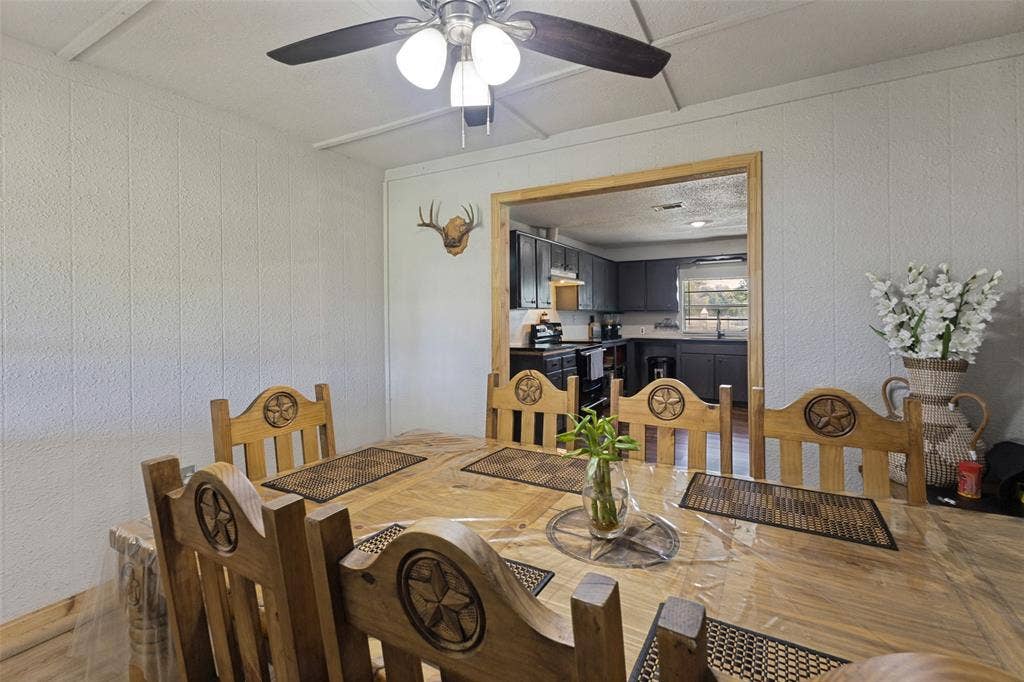 7400 County Road 131A, Terrell, TX 75161 Dining area featuring a central ceiling fan with multi-light fixture, wood-finish flooring, and a wide doorway framed in natural wood trim