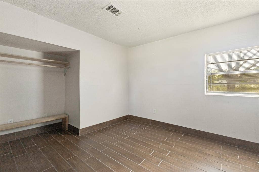 7400 County Road 131A, Terrell, TX 75161 Interior space featuring wood-finish tile flooring, white walls, a built-in recessed closet with shelving, and a horizontal window with installed blinds